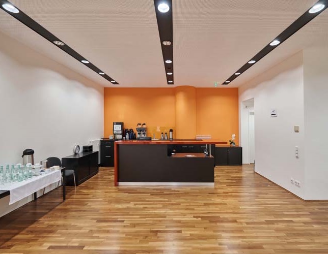 Foyer Konferenzbereich mit Parkettboden weiße-orangen Wänden Blick auf Theke