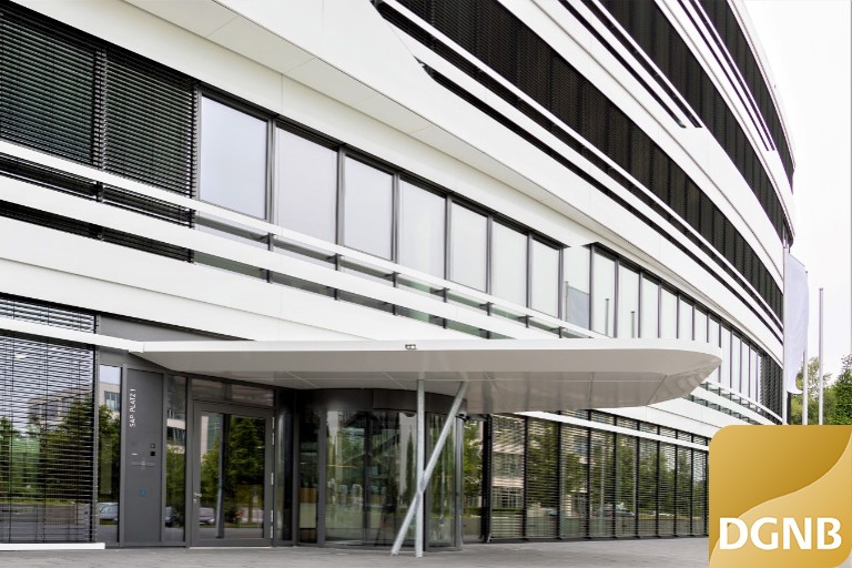 Triangulum Detail Eingang mit lang gezogenem Vordach und DGNB-Logo in Gold unten rechts.